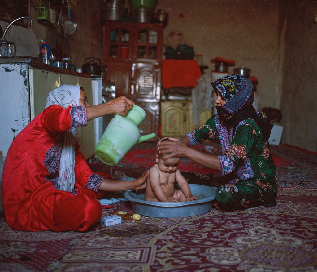 هاشم شاکری. از مجموعه‌ی Elegy for the Death of Hamun زنان روستای ریگ موری در حال شست‌وشوی یک کودک. در این روستا آب آشامیدنی تنها از 8 صبح تا 3 بعدازظهر در دسترس است.