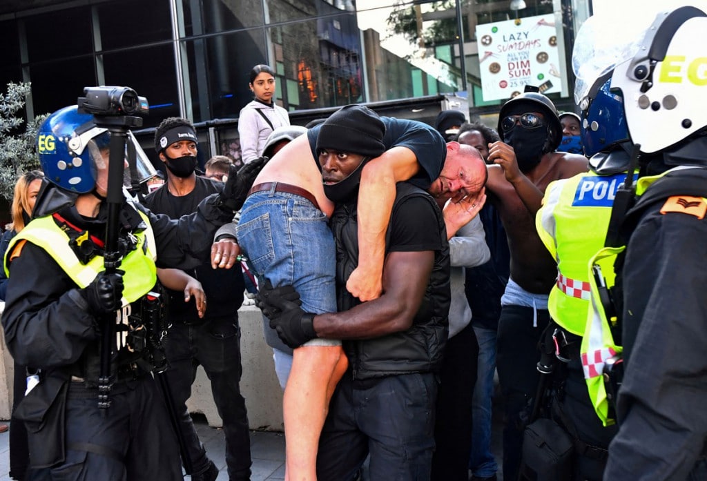 Dylan Martinez از رویترز. معترضی با نام Patrick Hutchinson در حال بردن یک ضد-معترض به جایی امن. در حوالی ایستگاه واترلو طی اعتراضات «زندگی سیاهان مهم است» در پی کشته شدن جورج فلوید به دست پلیس آمریکا. لندن، 13 ژوئن 2020
