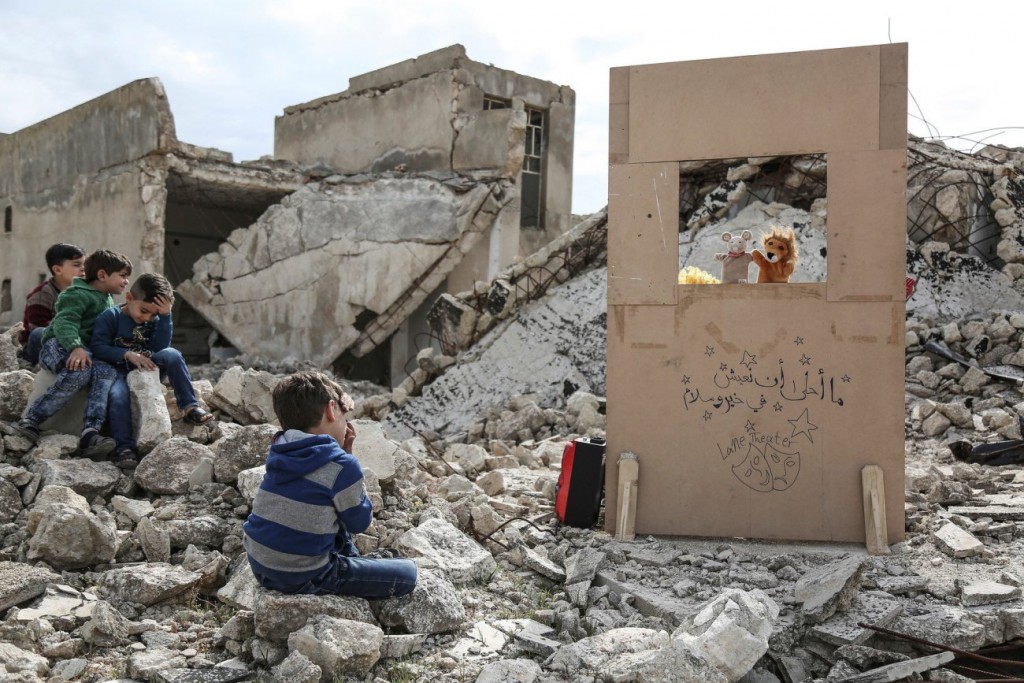 Anas Alkharboutli / DPA برای UNOCHA. «در میان آوار، عروسک‌گردان ولید راشد برای کودکان اجرای عروسکی می‌کند، سراقب، سوریه»، مارس 2019