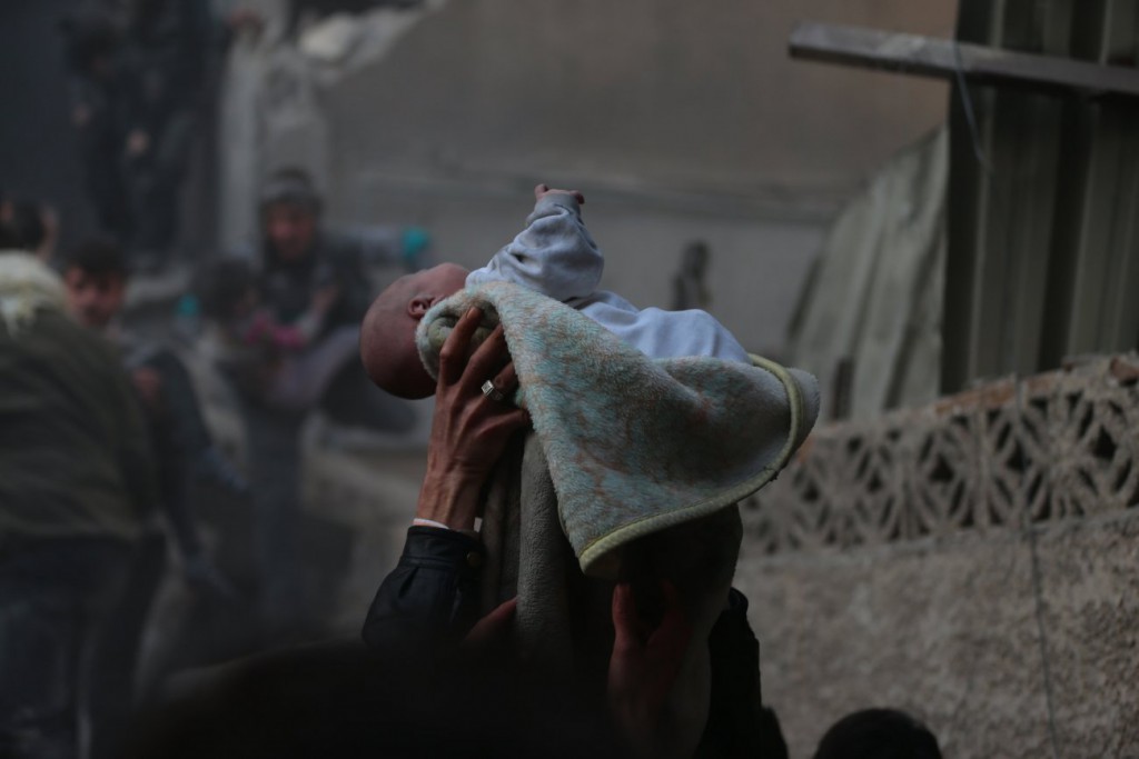 Bassam Khableh / رویترز برای UNOCHA. «یک نوزاد در میان آوار بمباران هوایی نجات یافته، دوما»، ژانویه 2014