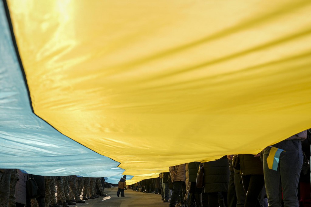 Vadim Ghirda از AP. کودکی زیر پرچم بزرگ اوکراین که توسط مردم در «روز اتحاد» حمل می‌شود. منطقه لوهانسک، شرق اوکراین، 27 بهمن 1400